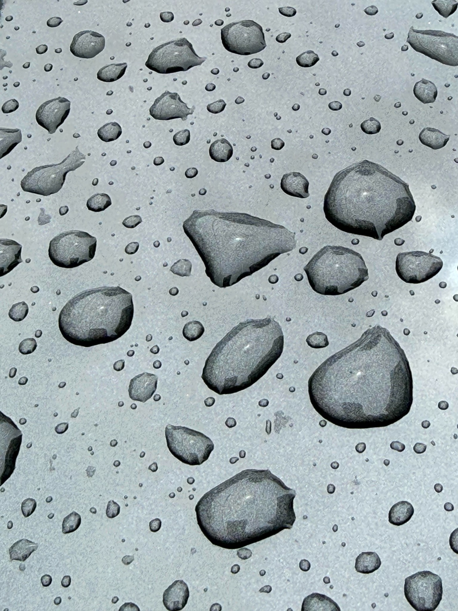 Raindrops clinging to the vertical silver panel of a car.